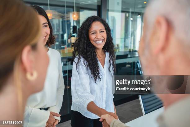group of business people greeting each other shaking hands in an office. - black business woman shaking hands stock pictures, royalty-free photos & images