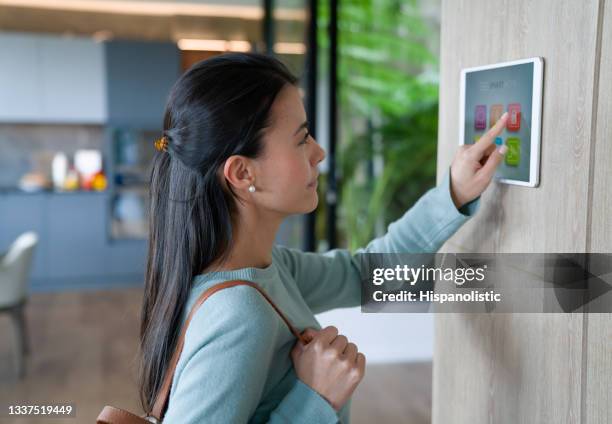 woman leaving her house and locking the door with an automated security system - burglar alarm stock pictures, royalty-free photos & images