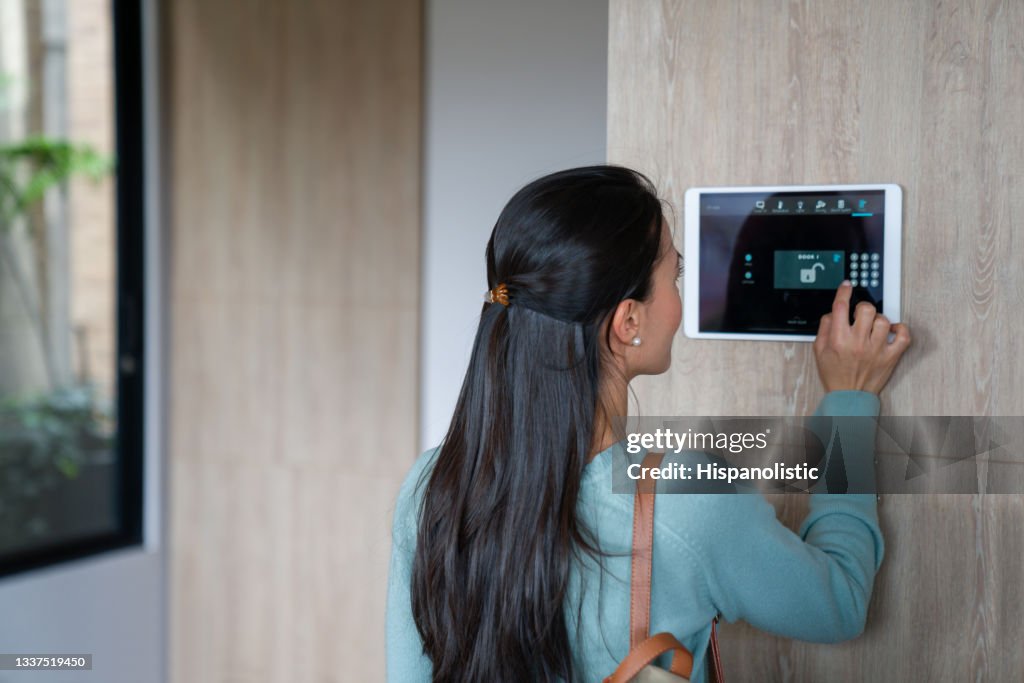 Mujer que ingresa pin para cerrar la puerta de su casa utilizando un sistema de domótica