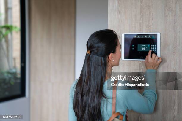 woman entering pin to lock the door of her house using a home automation system - beveiligingssysteem stockfoto's en -beelden