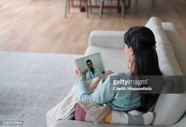woman at home feeling poorly and talking to her doctor on a video call - visit stock pictures, royalty-free photos & images
