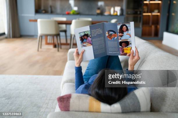 mujer relajándose en casa leyendo una revista - the magazines next event fotografías e imágenes de stock