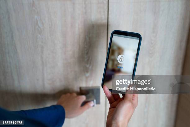 woman opening the door of her house using a home automation system - alarm system stock pictures, royalty-free photos & images