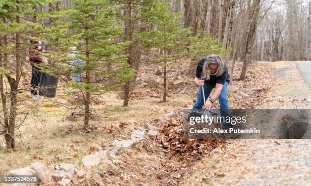 50-years-old man cleaning the backyard from old leaves. his teenage daughter is helping him. - 18 19 years stock pictures, royalty-free photos & images