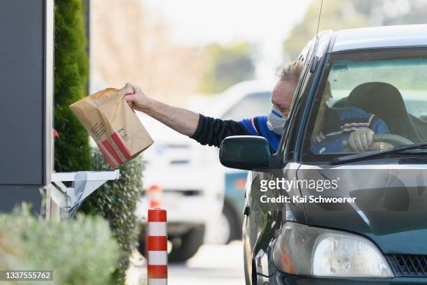 Customer takes his food bag at KFC Linwood on September 01, 2021 in Christchurch, New Zealand. Lockdown restrictions have eased across New Zealand to...