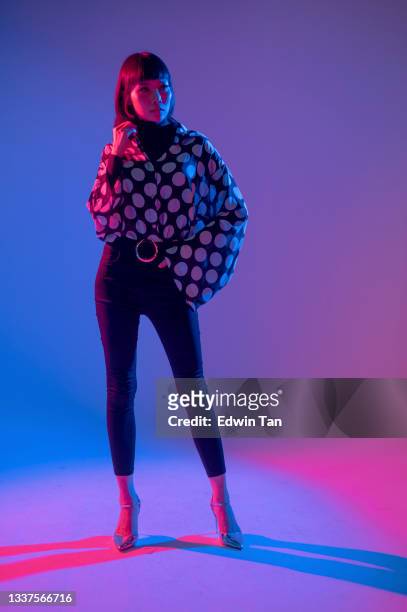 neon blue purple lights posing in studio asian chinese female fashion model with polka dot blouse in studio portrait - two tone color stock pictures, royalty-free photos & images