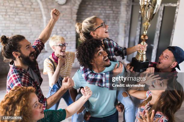 large group of happy creative people celebrating getting a trophy at casual office. - cas awards stock pictures, royalty-free photos & images