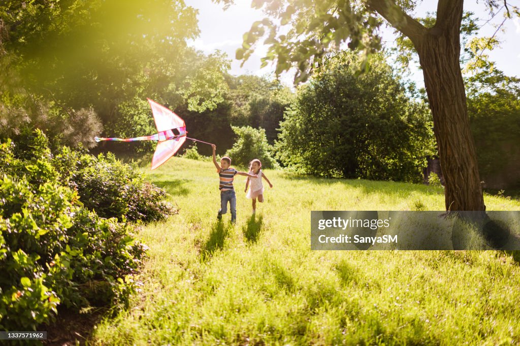 Beautiful children running in nature with kite