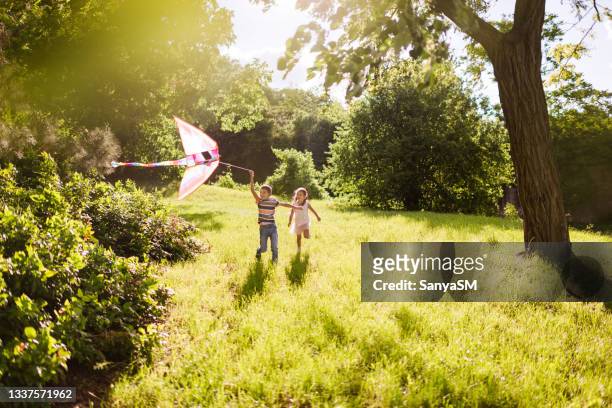beautiful children running in nature with kite - children only stock pictures, royalty-free photos & images