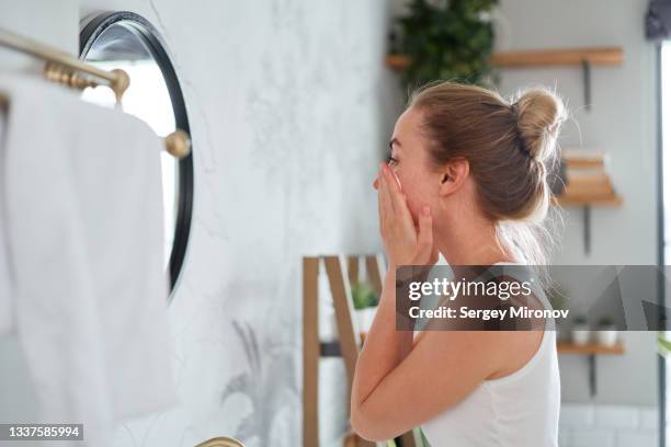young woman applying cream on face - body care and beauty stock pictures, royalty-free photos & images