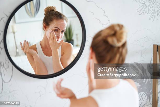 woman cleaning face with cosmetic product - clay mask stock pictures, royalty-free photos & images