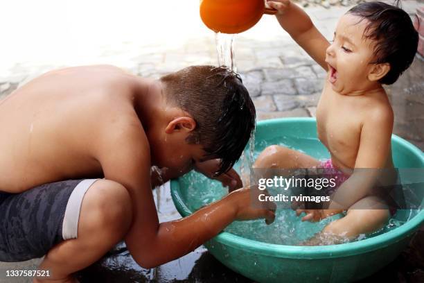 baby girl and her brother playing in the bath - washing tub stockfoto's en -beelden