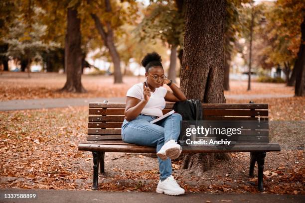 focused millennial black woman writing something in notebook - big beautiful black women 個照片及圖片檔