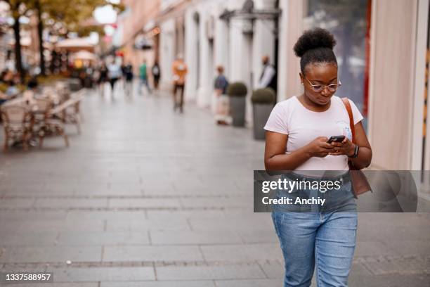 young woman using smart phone on a city street - big fat women stock pictures, royalty-free photos & images