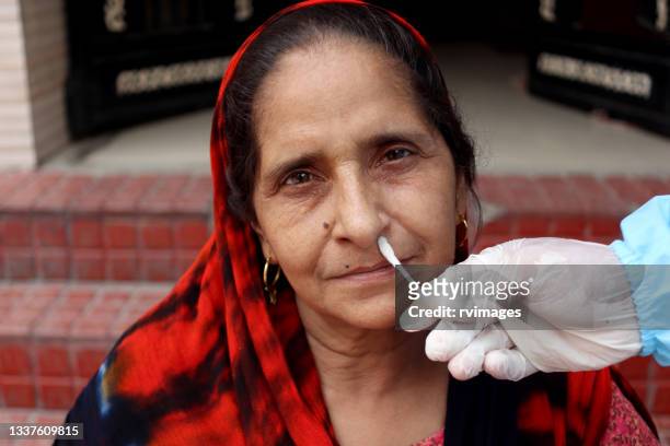 doctor in a protective suit taking a nasal swab from a person to test for possible covid-19 infection - india covid stock pictures, royalty-free photos & images