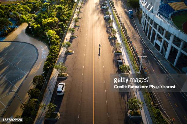 aerial drone view of shadow of man ride motorcycle on road at morning - städtische straße stock-fotos und bilder