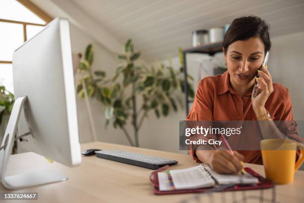 businesswoman multi-tasking while working in modern office - business talk stock pictures, royalty-free photos & images