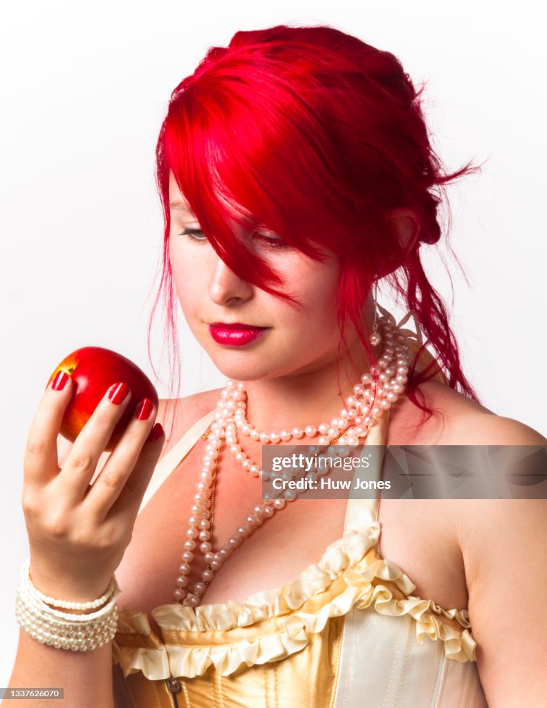Portrait of a woman with bright red hair with a red apple