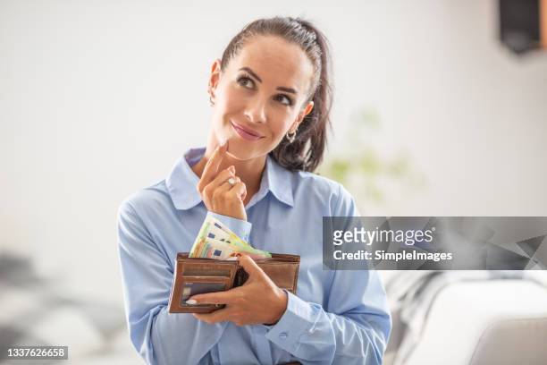woman holds an opened male wallet with cash thinking of spending the money. - salary stock pictures, royalty-free photos & images