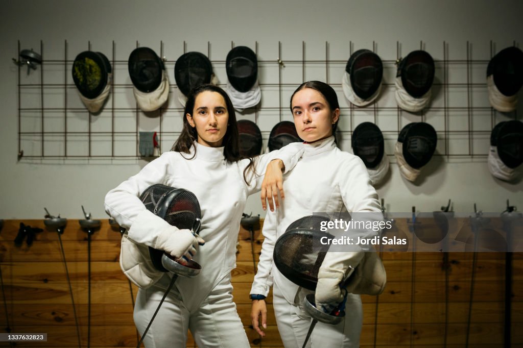Two young woman wearing a fencing protecting uniform