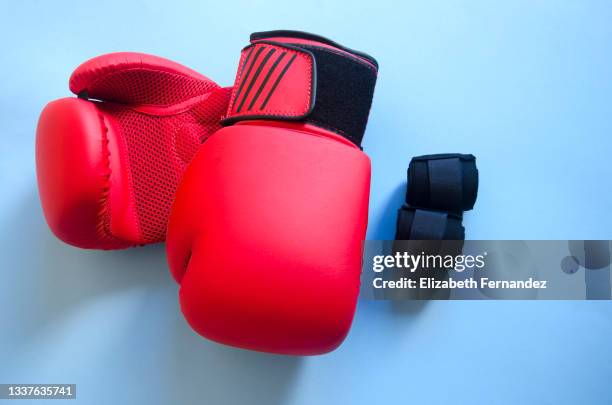 red boxing gloves and black bandages against blue background. boxing equipment. - boxing glove coloured background stock pictures, royalty-free photos & images