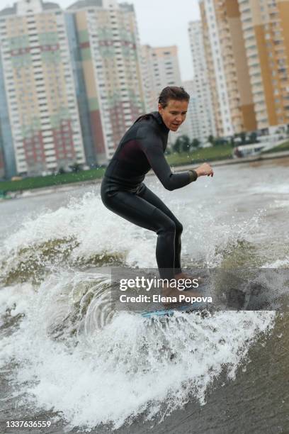 young adult woman wake surfing behind the boat - city to surf stock pictures, royalty-free photos & images