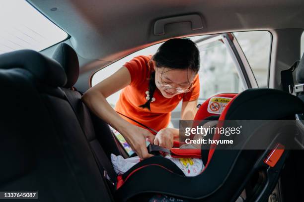 madre che allaccia la cintura di sicurezza per il suo bambino sul seggiolino di sicurezza dell'auto - child car seat foto e immagini stock