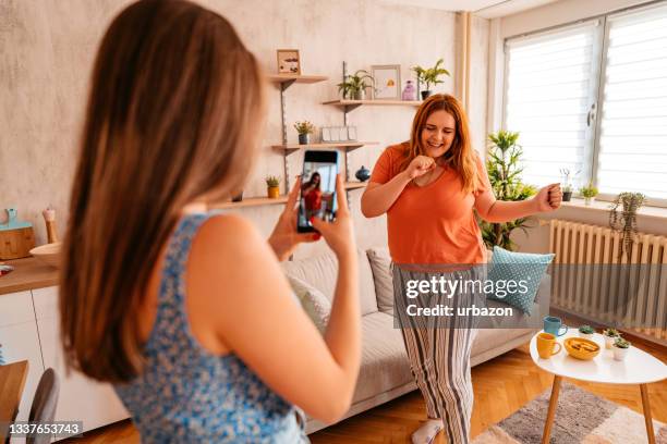 woman taking photo of friend singing and dancing - fat woman dancing stockfoto's en -beelden