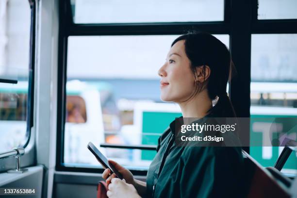 young asian woman using smartphone while riding on local city tram commuting in the city - day in the life fotografías e imágenes de stock