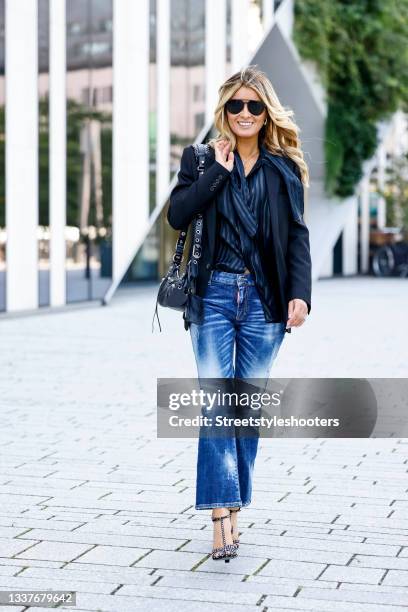 Influencer Gitta Banko wearing a dark blue blazer by Saint Laurent, a blue and black striped lavalliere blouse by Saint Laurent, blue flared stone...