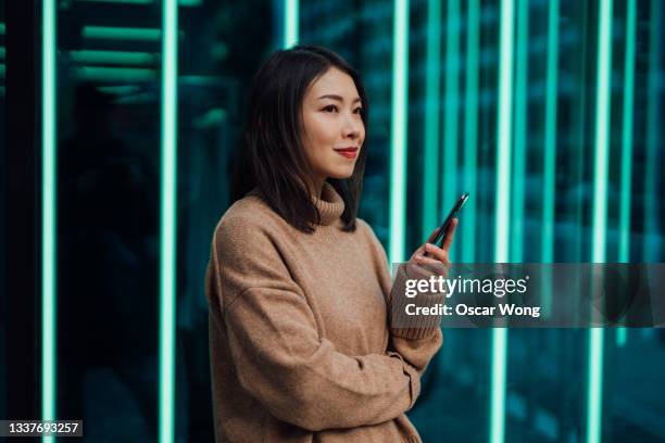 young woman using mobile phone against futuristic holographic background - bc fotografías e imágenes de stock