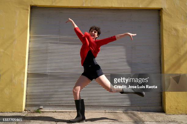 happy woman jumping over urban pavement against wall - modeshow stock-fotos und bilder