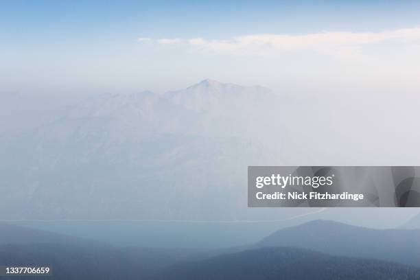a forest fire smoke filled scene with lake minnewanka and mt costigan from near the summit of mt peechee, banff national park, alberta, canada - costigan stock pictures, royalty-free photos & images