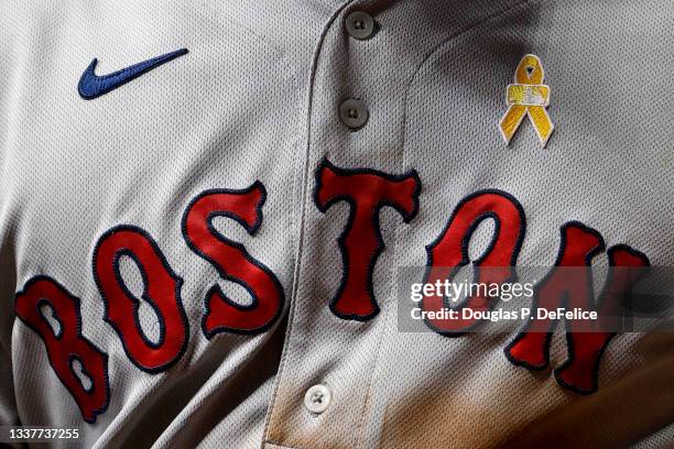 Detailed view of the front of the jersey worn by Kyle Schwarber of the Boston Red Sox with a yellow ribbon representing Childhood Cancer Awareness...