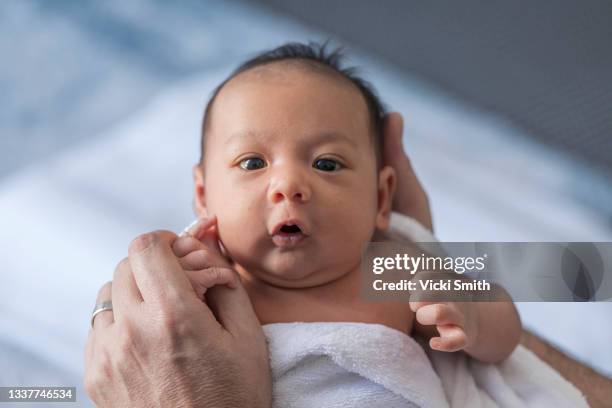 close up photo of a one week old baby boy with dark hair and eyes open, mixed race, asian and caucasian - ik stockfoto's en -beelden