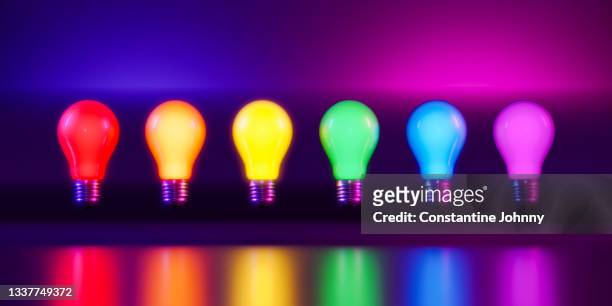 row of illuminated rainbow colored light bulbs - lightbulbs in a row stock pictures, royalty-free photos & images
