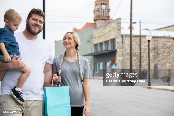 young family walking in city and shopping together - small business saturday stock pictures, royalty-free photos & images