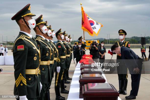 Chinese Ambassador to South Korea Xing Haiming bows in front of caskets containing the remains of Chinese soldiers with Chinese national flags during...