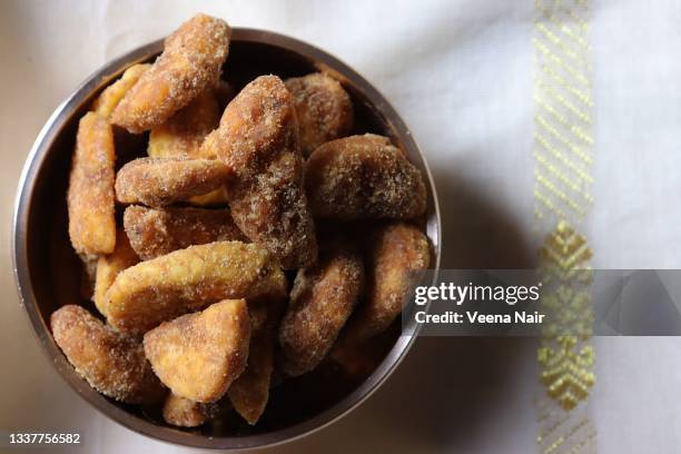 sharkara varatti/upperi/jaggery coated banana chips in brass uruli/kerala/onam festival - jaggery stock pictures, royalty-free photos & images