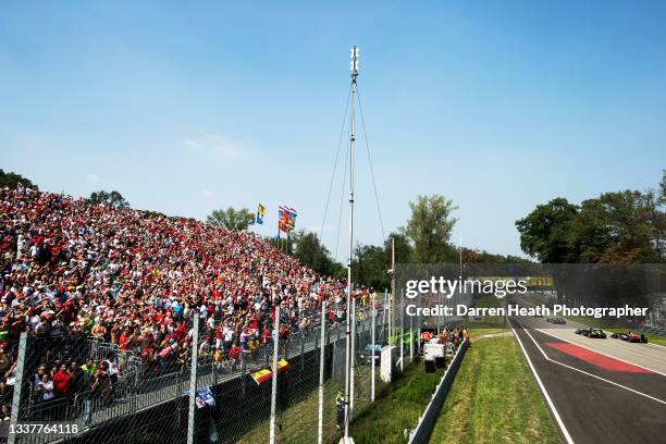 Thousands of fans and spectators standing and sitting in the grandstand with Dutch, Asturias, Ferrari and Italian flags blowing in the wind while...