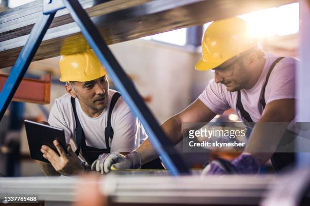 two metal workers cooperating while working with iron in aluminum mill. - hard hat worker stock pictures, royalty-free photos & images