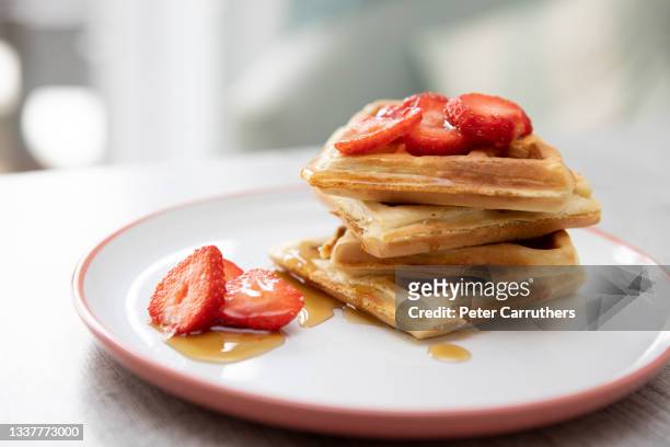 stack of american style waffles with strawberries and maple syrup  on a plate - waffles stock pictures, royalty-free photos & images