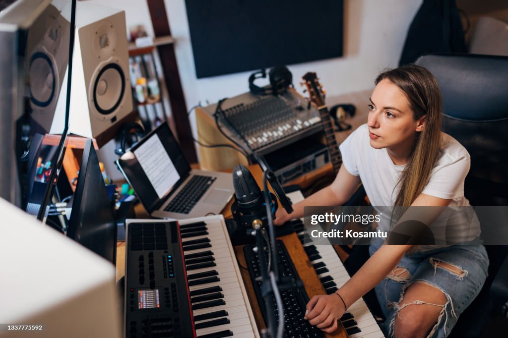 Focused female music producer, in her music studio following the sound record on her screen, working on post-production part