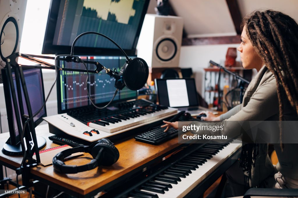 Cool and creative female artist, working on audio production, from her home, in her modern music studio