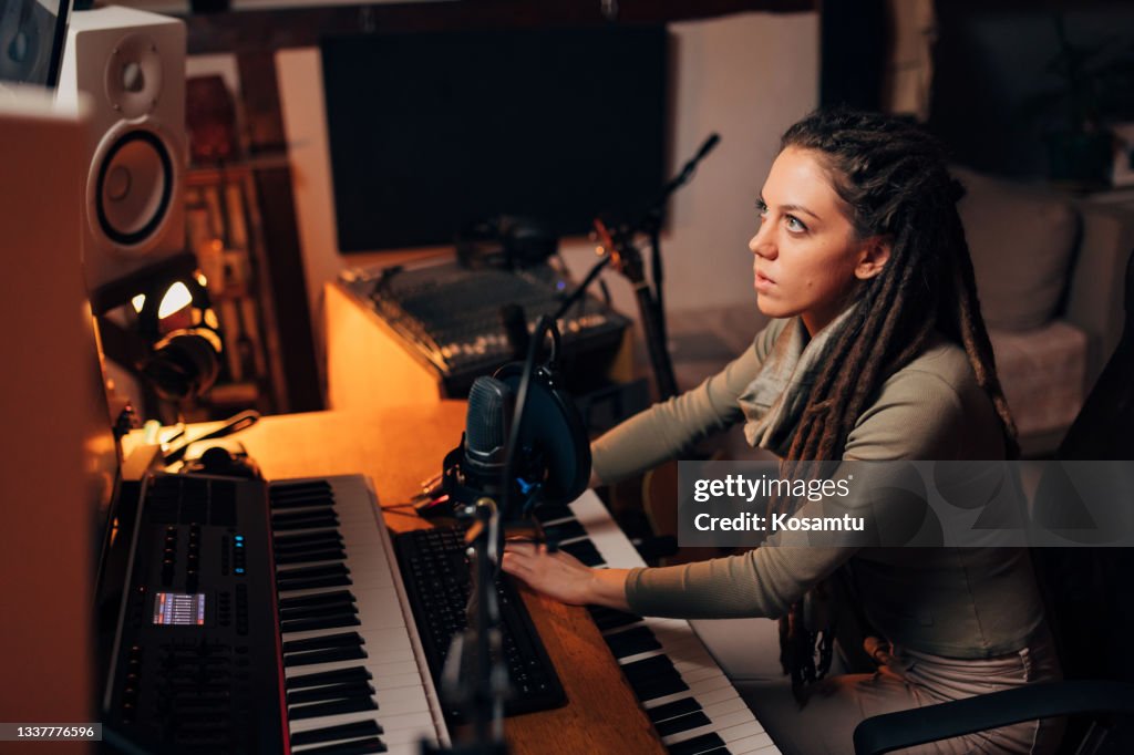 Dedicated female producer working on music track on sound mixer control panel in music studio studio