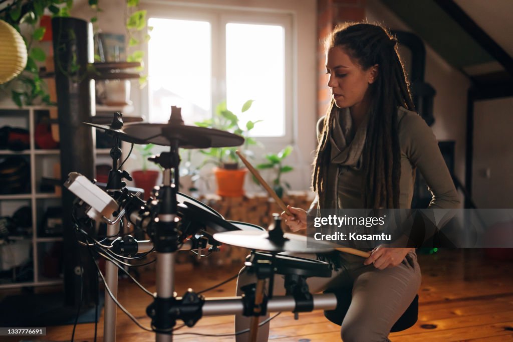 Passionate female musician, and drummer, in her studio practising her skills