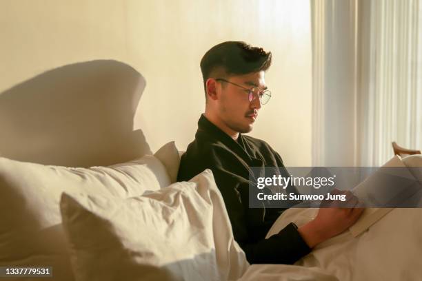 man with notebook on bed in hotel room - tagebuch stock-fotos und bilder