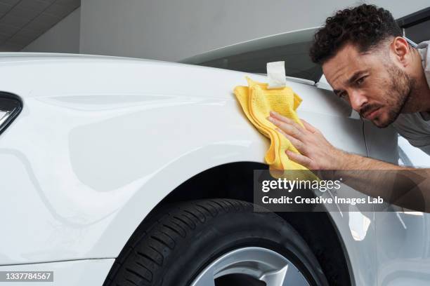 worker man wiping a car with a rag while polishing it. - mikrofaser stock-fotos und bilder