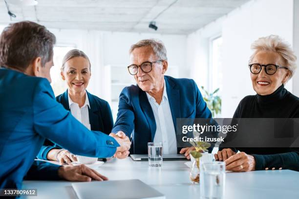 senior businessmen shaking hands - shareholder stockfoto's en -beelden