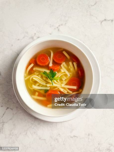 bowl of chicken soup with noodles on white background - sopa de pollo con fideos fotografías e imágenes de stock